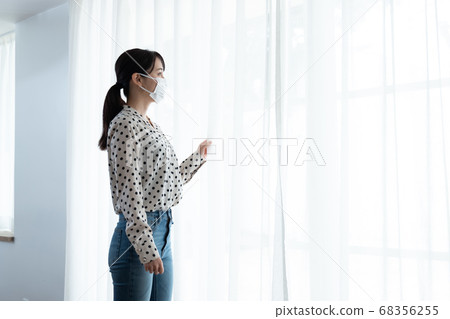 Woman wearing a mask and standing on the windowsill Woman wearing a mask and standing on the windowsill 68356255