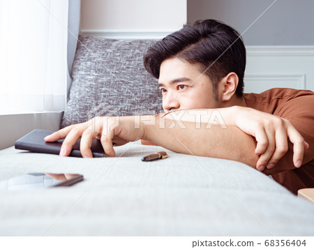 Young asian man taking break after reading book at 68356404