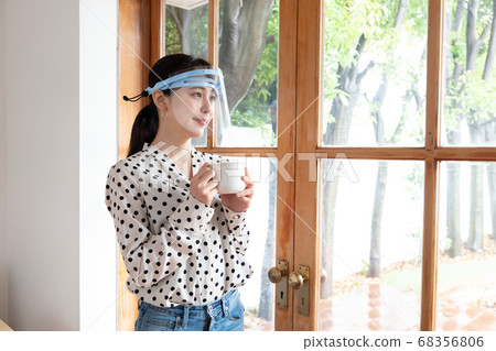A woman wearing a face shield and standing on the windowsill A woman wearing a face shield and standing on the windowsill 68356806