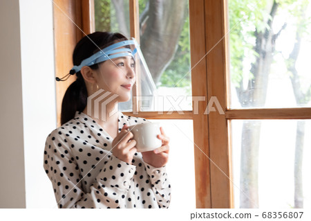 一個女人戴著口罩,站在窗台上 一個女人戴著口罩,站在窗台上 68356807