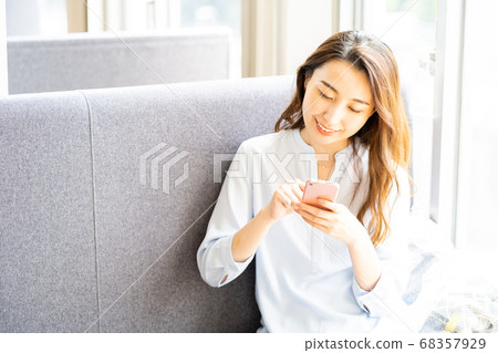 A young woman operating a smartphone on the sofa. A young woman operating a smartphone on the sofa. 68357929