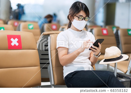 Young female wearing face mask and using mobile 68358182