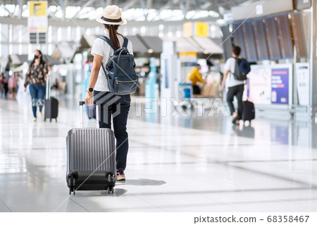 Young female wearing face mask with luggage Young female wearing face mask with luggage 68358467