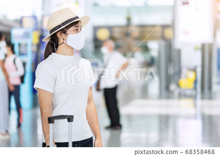 Young female wearing face mask with luggage Young female wearing face mask with luggage 68358468