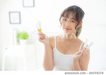 Beautiful portrait young asian woman holding and presenting cream or lotion product. Beautiful portrait young asian woman holding and presenting cream or lotion product. 68359259