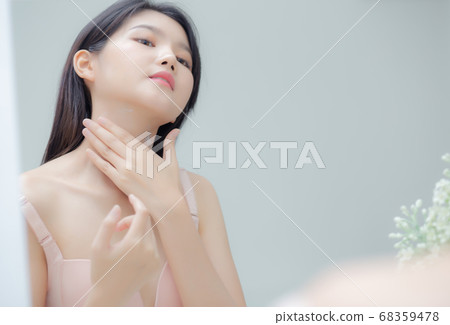 Beautiful sexy young asian woman looking mirror applying cream on neck and message. Beautiful sexy young asian woman looking mirror applying cream on neck and message. 68359478