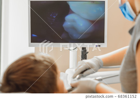 A young female dentist examines the teeth of a boy 68361152