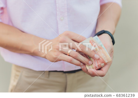 A close up photo of a Caucasian male hand holding a 100 Russian ruble note. 68361239