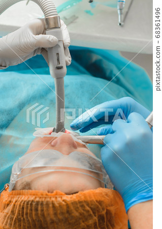 Dentist ultrasound removes stones on the teeth of a woman with a dental pad on her mouth. 68361496