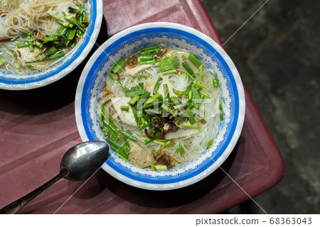 Soup called hu tieu go (noodle, meat products, herbs) on a shabby red plastic table in the street in Ho Chi Minh City, for 15 000 dongs (0.65 USD) a bowl. A budget food popular in Saigon, Vietnam. Soup called hu tieu go (noodle, meat products, herbs) on a shabby red plastic table in the street in Ho Chi Minh City, for 15 000 dongs (0.65 USD) a bowl. A budget food popular in Saigon, Vietnam. 68363043