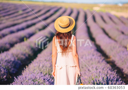 Woman in lavender flowers field in white dress and hat 68363053