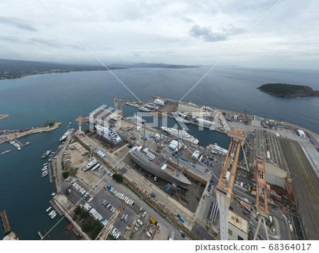 Aerial view of dry dock in La Ciotat city, France, the cargo crane, boats on repair, a luxury sail yacht and motor yacht in dry dock, mountain is on background Aerial view of dry dock in La Ciotat city, France, the cargo crane, boats on repair, a luxury sail yacht and motor yacht in dry dock, mountain is on background 68364017