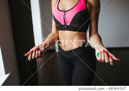 Sporty woman exercising with skipping rope 68364107