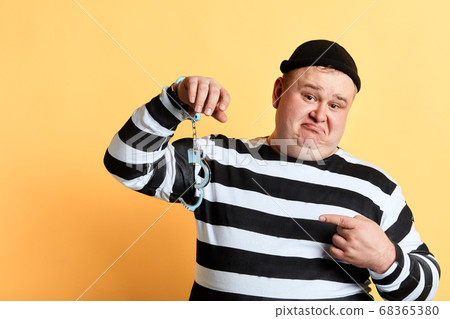 sad unhappy fat man pointing to unlocked handcuffs hanging on his hand sad unhappy fat man pointing to unlocked handcuffs hanging on his hand 68365380
