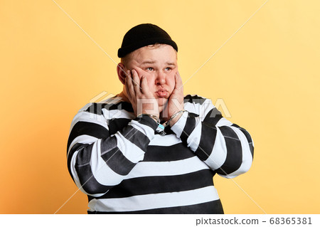 unhappy upset fat thief touching his cheek, thinking about his crime unhappy upset fat thief touching his cheek, thinking about his crime 68365381