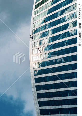 High-rise workers wash windows on top of building 68365607