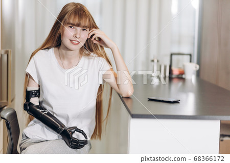 awesome girl with a cyber arm leaning on the table and looking at the camera awesome girl with a cyber arm leaning on the table and looking at the camera 68366172