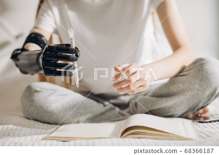 disabled girl tries to hold a pen with an artificial arm disabled girl tries to hold a pen with an artificial arm 68366187