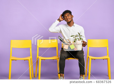 disappointed young dark-skinned man holding box of personal belongings quit job 68367326