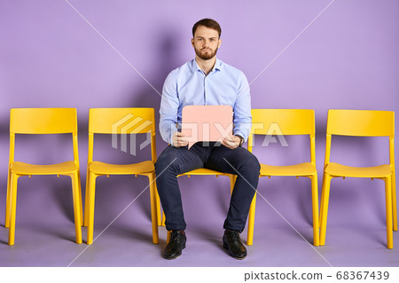 Upset young man sitting on the yellow chair with blank thought bubble Upset young man sitting on the yellow chair with blank thought bubble 68367439
