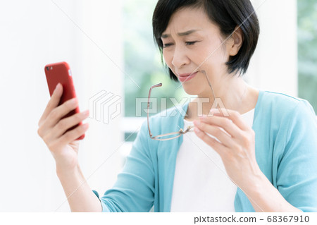 A middle-aged woman who suffers from presbyopia [Smartphone] 68367910
