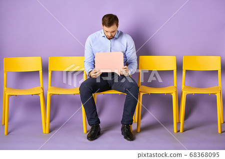 Young man sitting on chair looking at blank thought bubble Young man sitting on chair looking at blank thought bubble 68368095