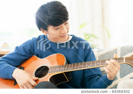 A young man playing the guitar A young man playing the guitar 68368302
