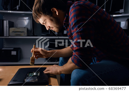 cheerful excited guy concentrated on fixing a laptop cheerful excited guy concentrated on fixing a laptop 68369477