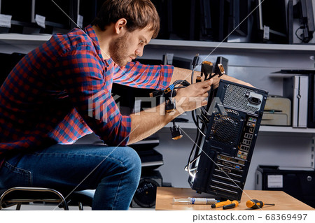 young technician replacing the wires of the system unit 68369497