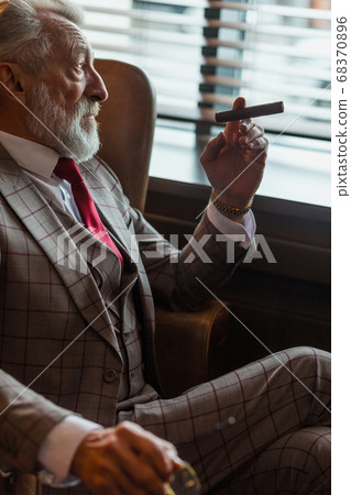 Serene concentrated mature male architector with grey-haired beard smoking cigar Serene concentrated mature male architector with grey-haired beard smoking cigar 68370896