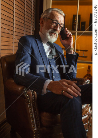 Experienced old private physician talking on smartphone with patient indoors. Experienced old private physician talking on smartphone with patient indoors. 68373246