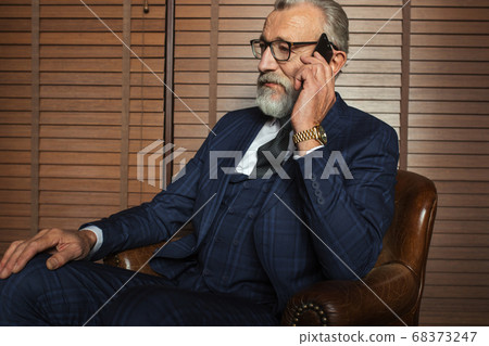 Experienced old private physician talking on smartphone with patient indoors. Experienced old private physician talking on smartphone with patient indoors. 68373247
