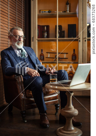 Senior dramatist looking at laptop, creating novel while sitting Senior dramatist looking at laptop, creating novel while sitting 68373268