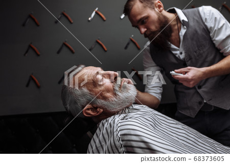 Old man getting his beard shaved by barber 68373605