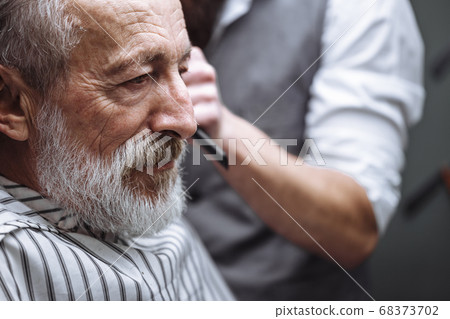 Close up of a hairdresser s work for a handsome old man at the barber shop. Close up of a hairdresser s work for a handsome old man at the barber shop. 68373702