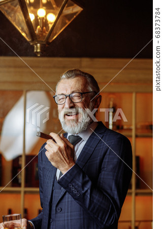 Elderly businessman in formal suit with whiskey and cigar at lux Elderly businessman in formal suit with whiskey and cigar at lux 68373784