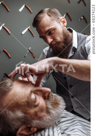 Old man getting his beard shaved by barber Old man getting his beard shaved by barber 68374123