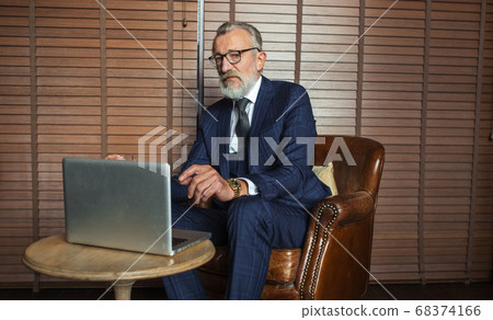 Senior dramatist looking at laptop, creating novel while sitting in pub. Senior dramatist looking at laptop, creating novel while sitting in pub. 68374166