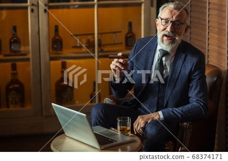 Senior dramatist looking at laptop, creating novel while sitting in pub. Senior dramatist looking at laptop, creating novel while sitting in pub. 68374171