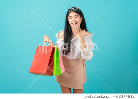 Woman holding multi coloured shopping bags and announcing with hands to the mouth. 68374612