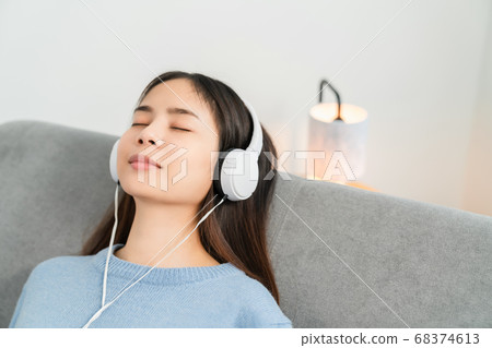 Asian woman of happy smiling are listening to music from white headphones on vacation in the house. 68374613