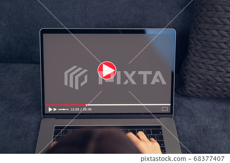 Woman watching video online on laptop. 68377407