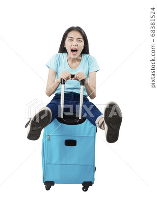 Asian woman with happy expression sitting on suitcase 68381524