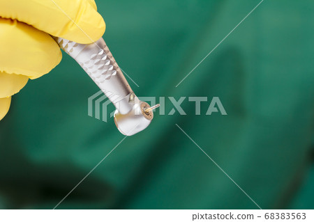 Dentist's hand in glove with dental handpiece. 68383563