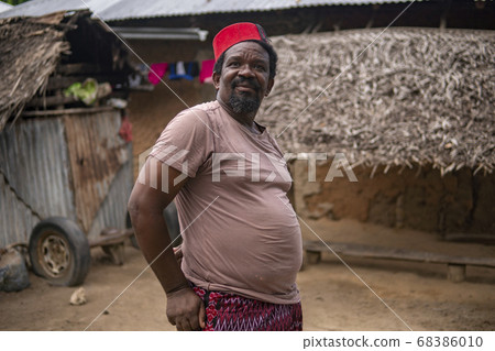 An African Older Man in Red Muslim Taqiyyah Fez Hat posing with a stick for lame people on Yard Near the Basic Hut with Thatched roof in Small Remote Village in Tanzania, Pemba island, Zanzibar An African Older Man in Red Muslim Taqiyyah Fez Hat posing with a stick for lame people on Yard Near the Basic Hut with Thatched roof in Small Remote Village in Tanzania, Pemba island, Zanzibar 68386010