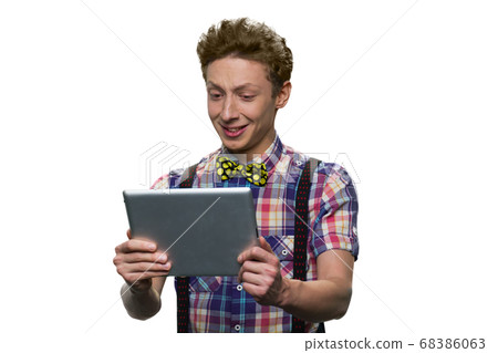 Teenage boy with facial expression of bewilderment or discontent is looking at tablet pc. Teenage boy with facial expression of bewilderment or discontent is looking at tablet pc. 68386063