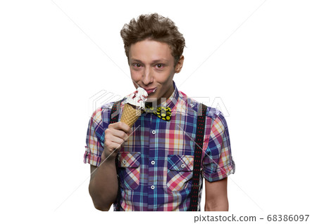Portrait of male teenager is eating ice-cream against white background. Portrait of male teenager is eating ice-cream against white background. 68386097
