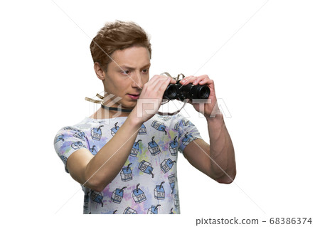 Caucasian teen boy is looking through binoculars. Caucasian teen boy is looking through binoculars. 68386374