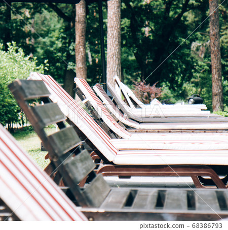 Wooden sun loungers by the swimming pool on a summer day Wooden sun loungers by the swimming pool on a summer day 68386793