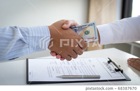 Businessmen make dollar payments while signing an investment agreement to be a partner in an illegal and successful manner, Bribery and corruption concept. Businessmen make dollar payments while signing an investment agreement to be a partner in an illegal and successful manner, Bribery and corruption concept. 68387670